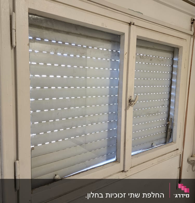 חלון זכוכית עם תריסים סגורים למחצה